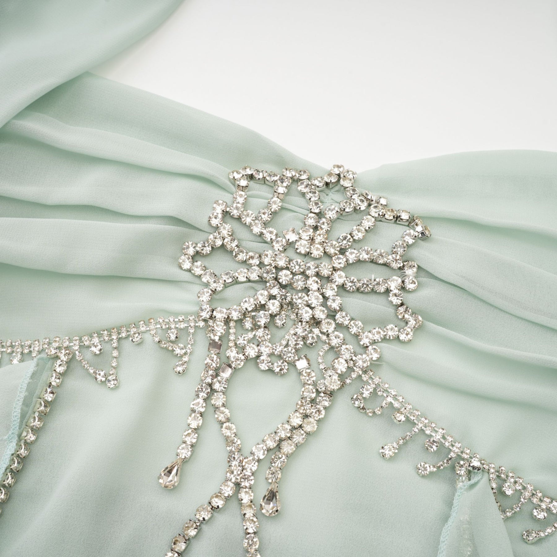 A woman wearing a midi length dress with ruffled details and embellishments named Salilah The dress features a fitted bodice and flowy skirt