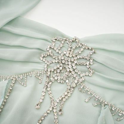 A woman wearing a midi length dress with ruffled details and embellishments named Salilah The dress features a fitted bodice and flowy skirt