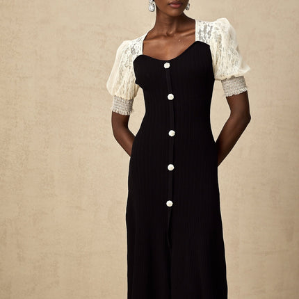 A woman wearing a midi length knit dress with lace trim details along the neckline and hem standing in a neutral pose against a plain background