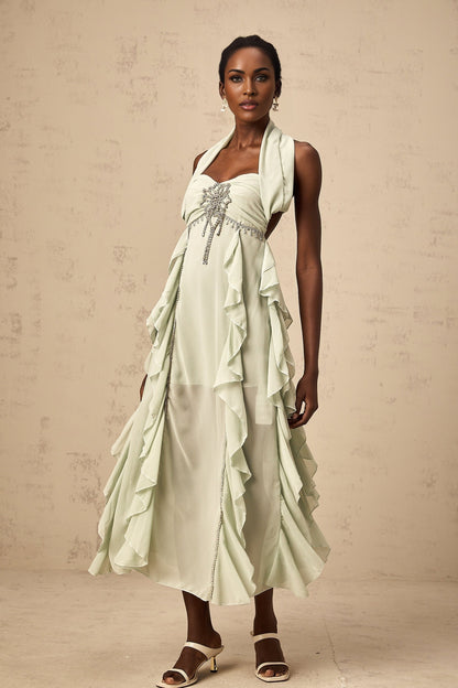 A woman wearing a midilength dress with ruffled details and embellishments named Salilah