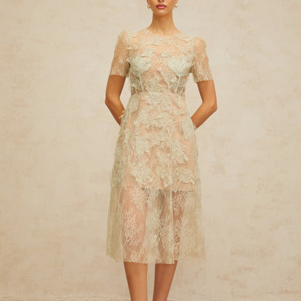 A woman wearing a mintgreen midi dress with delicate floral lace pattern standing in a relaxed pose