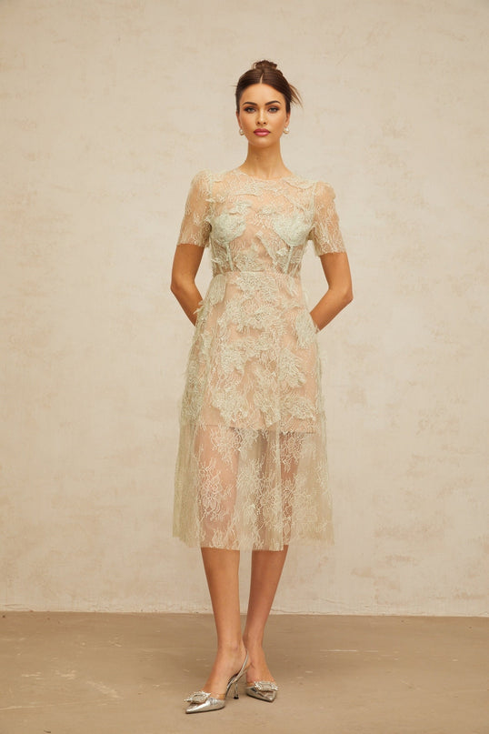 A woman wearing a mintgreen midi dress with delicate floral lace pattern standing in a relaxed pose