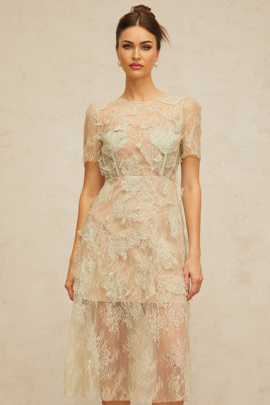 A woman wearing a mintgreen midi dress with floral lace pattern standing in a relaxed pose