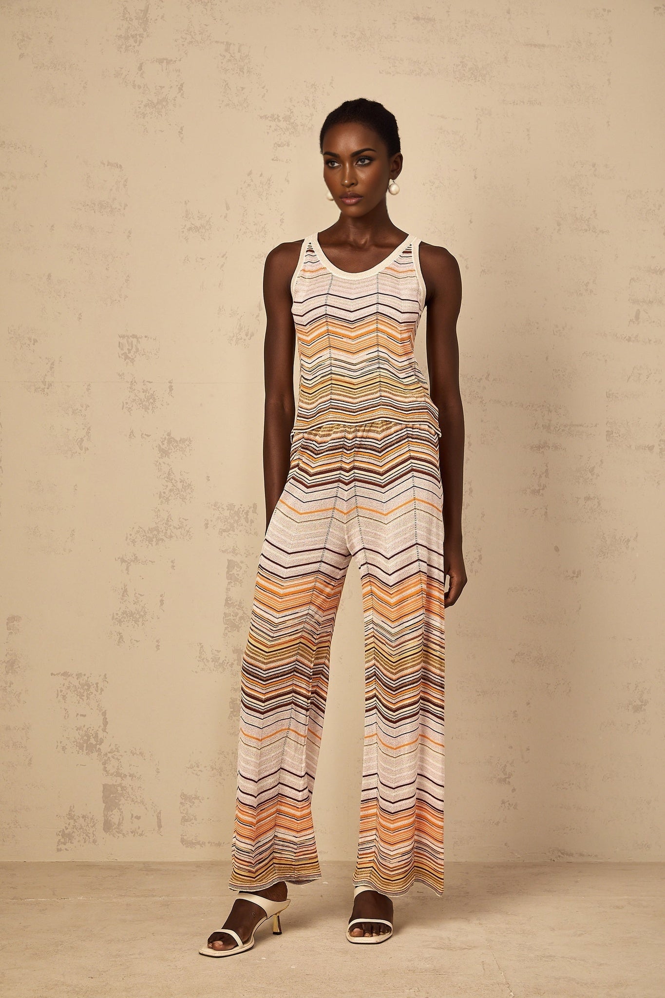 A woman wearing a neutralcolored striped knit matching set consisting of a top and bottom by Chloé standing in a relaxed pose