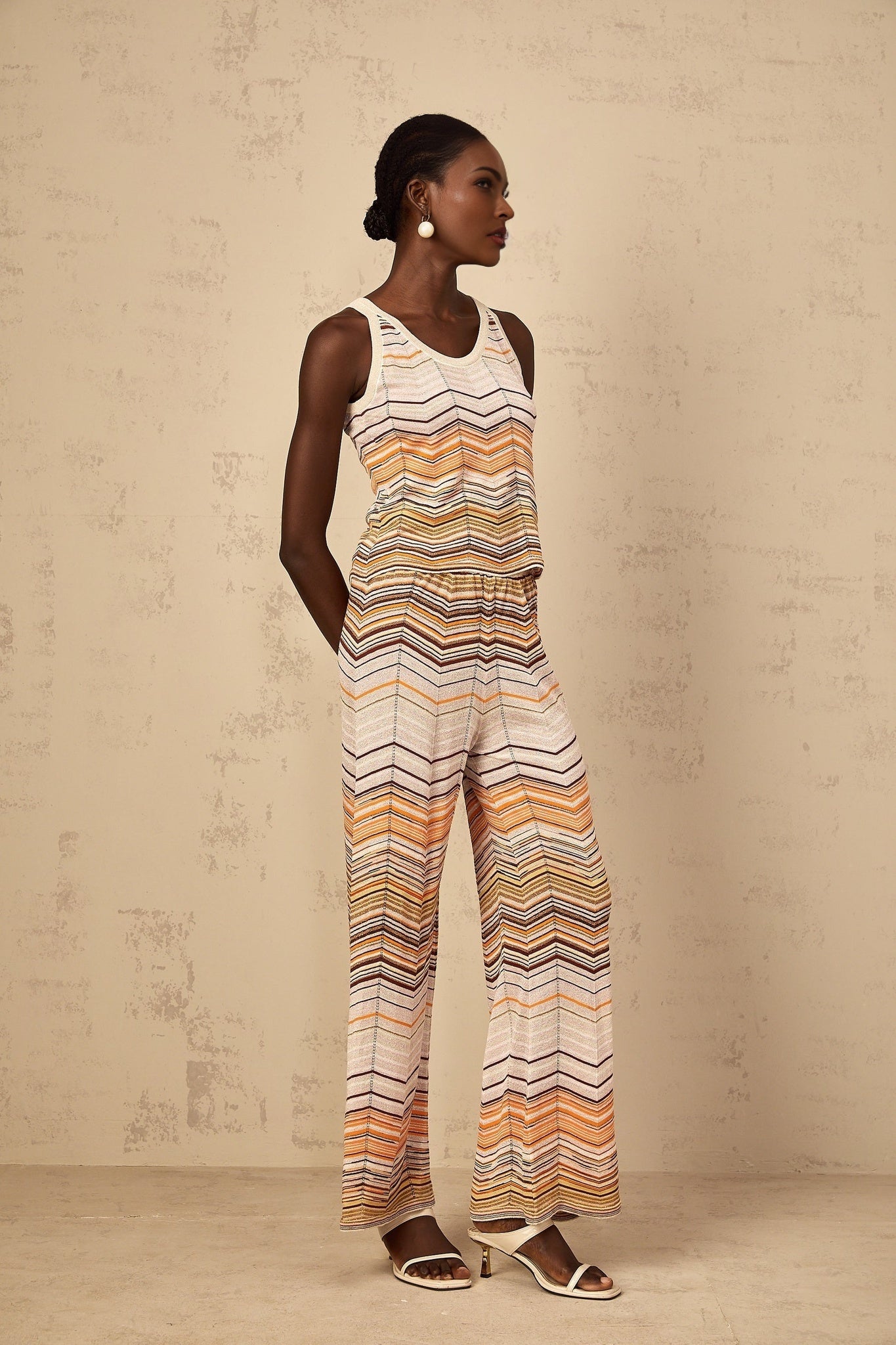 A woman wearing a neutralcolored striped knit matching set consisting of a top and bottoms from Chloe