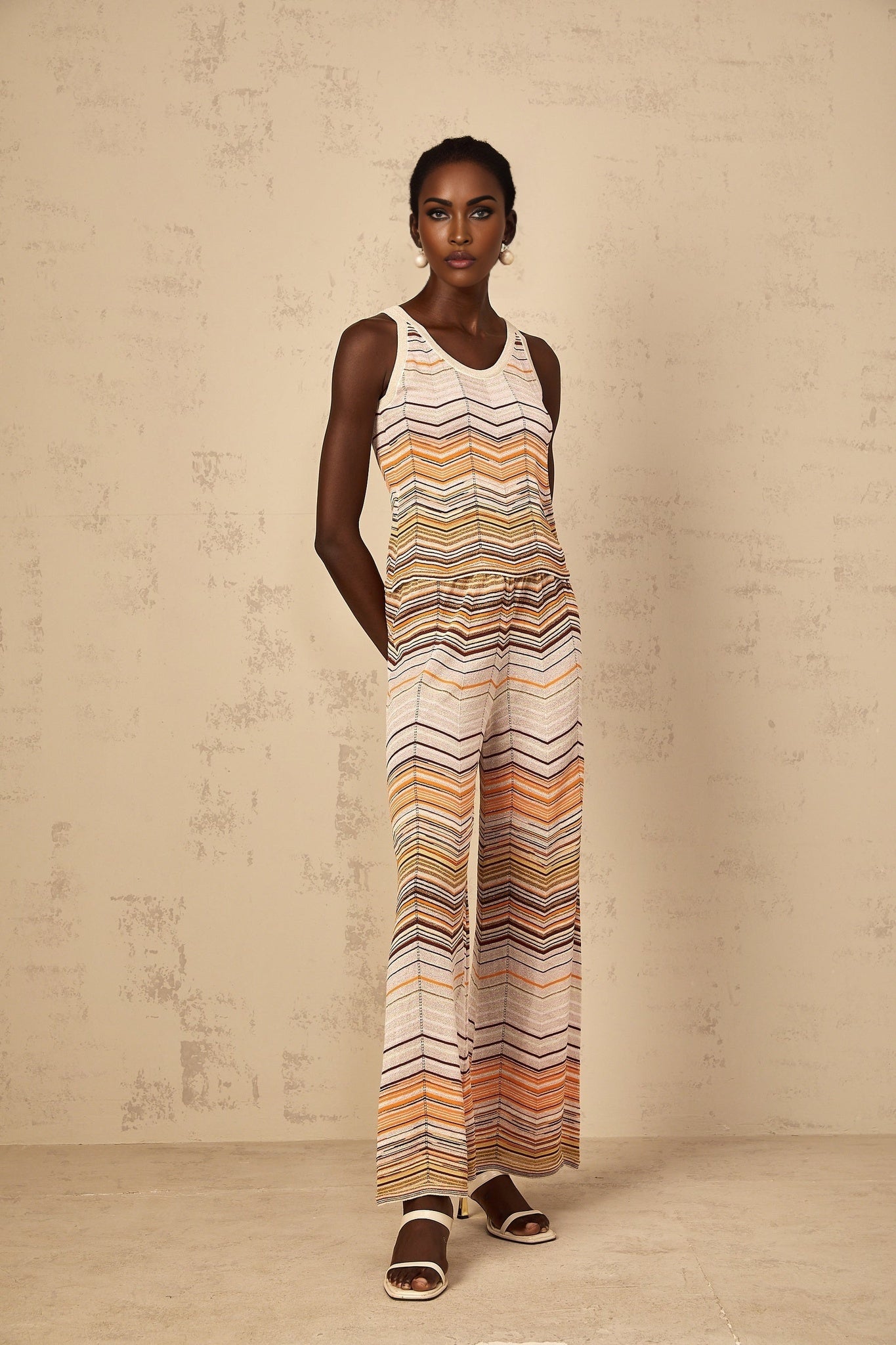 A woman wearing a neutralcolored striped knit matching set from Chloe featuring a top and bottom with a coordinated pattern