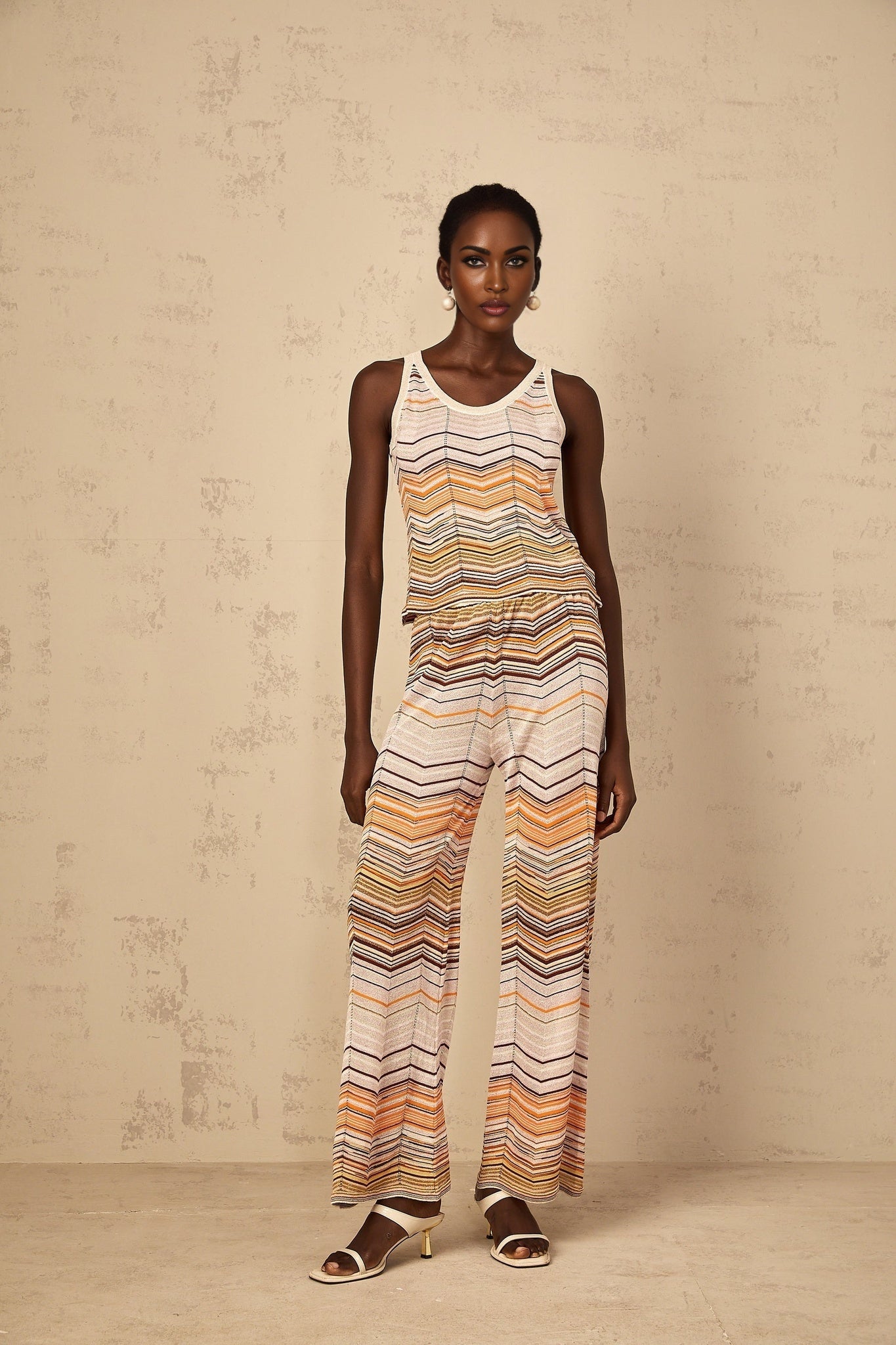 A woman wearing a neutraltoned striped knit matching set consisting of a longsleeved top and pants from Chloe standing in a relaxed pose