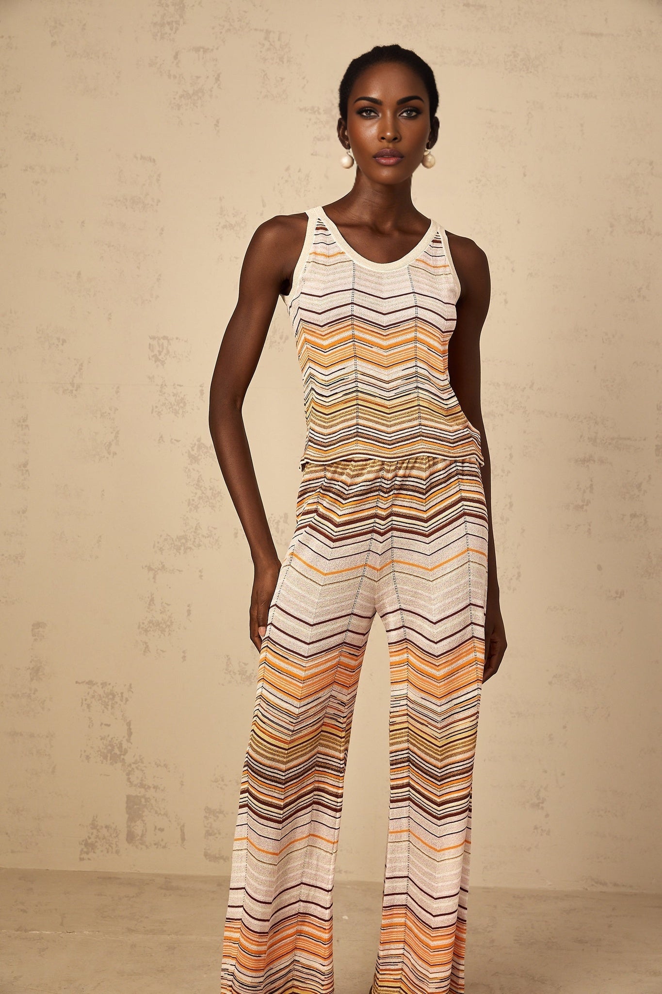 A woman wearing a neutraltoned striped knit matching set consisting of a top and pants from Chloe standing in a relaxed pose