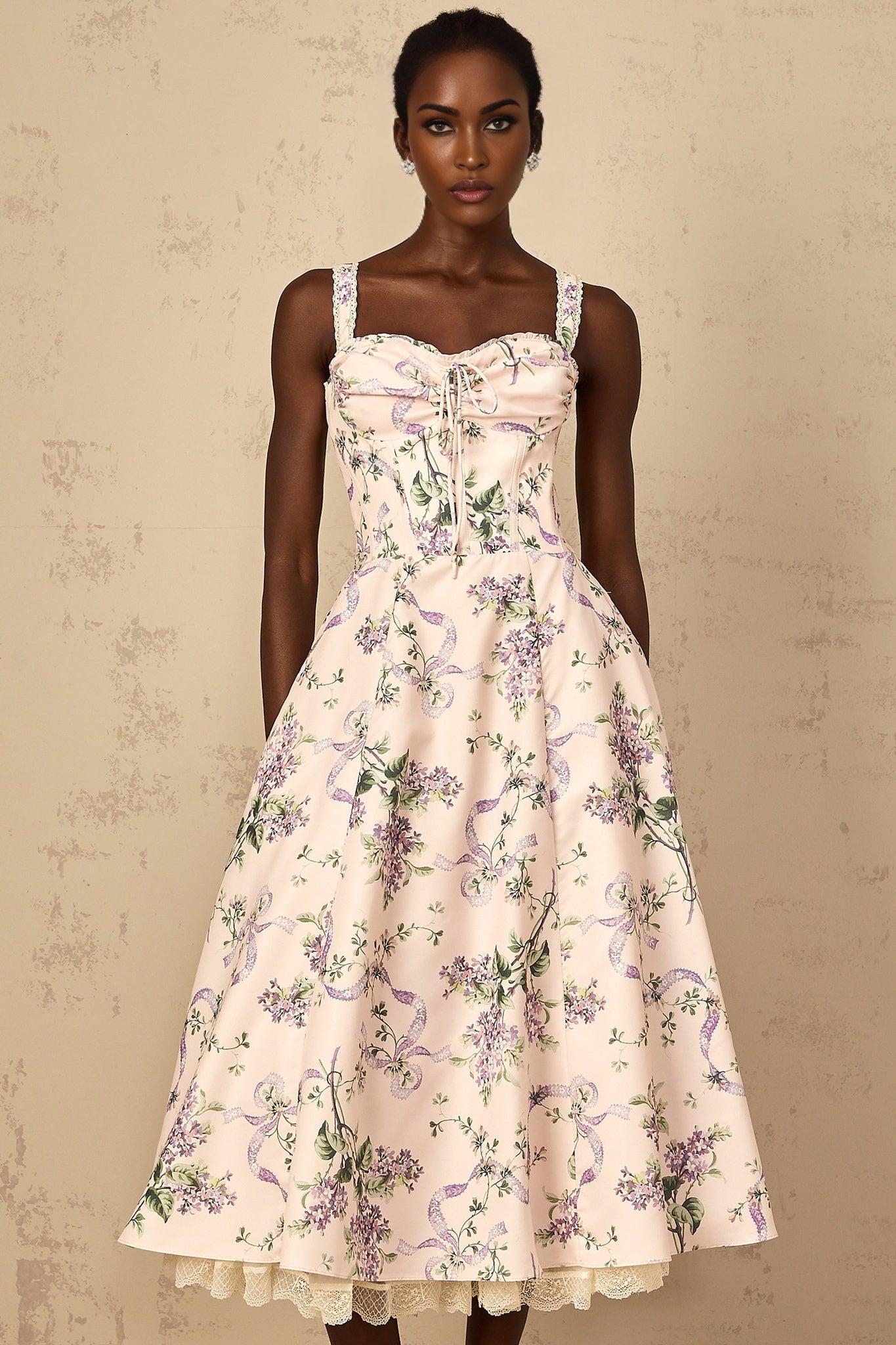 A woman wearing a pink midi dress with a floral print and shirred detailing