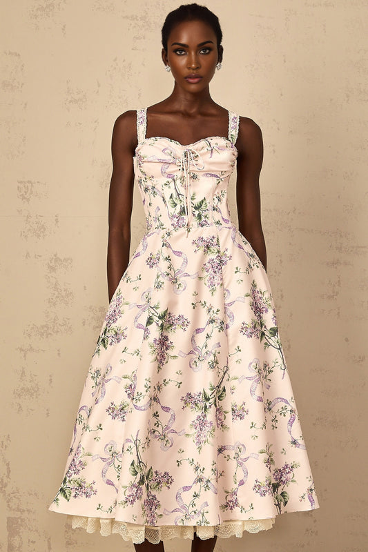 A woman wearing a pink midi dress with a floral print and shirred detailing