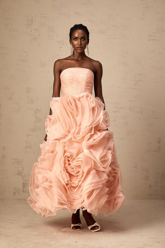A woman wearing a pink offshoulder midi dress with 3D petal details made of tulle fabric The dress has a fitted bodice and flared skirt ending at mid calf length