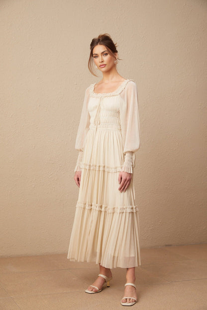 A woman wearing a pleated metallic midi dress with shirred detailing and a flowy silhouette named Camille