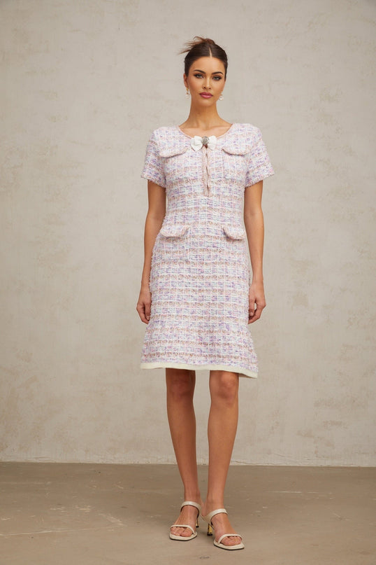 A woman wearing a purple checkered knit midi dress with long sleeves and a fitted silhouette standing against a plain background