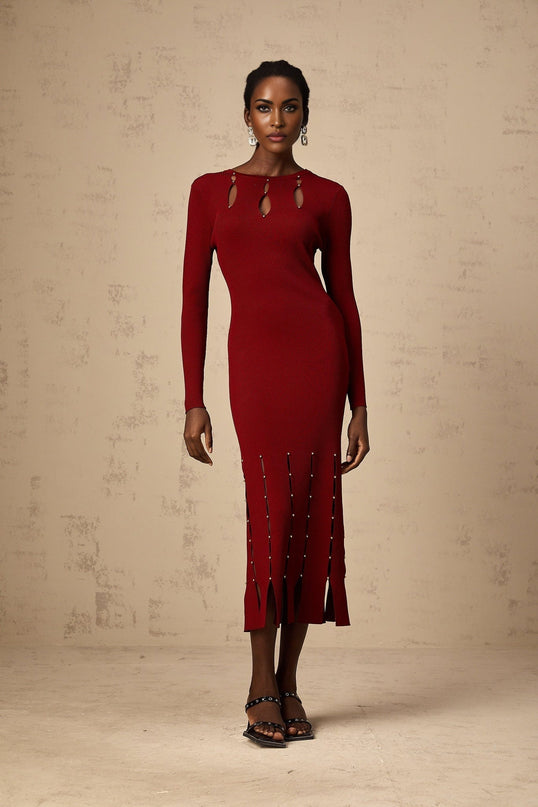 A woman wearing a red knit midi dress with long sleeves beaded details and cutout sections