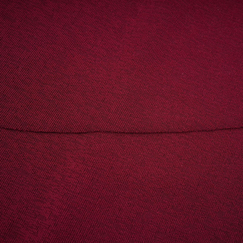 A woman wearing a red midi dress with ruched detailing and a flap design on the front