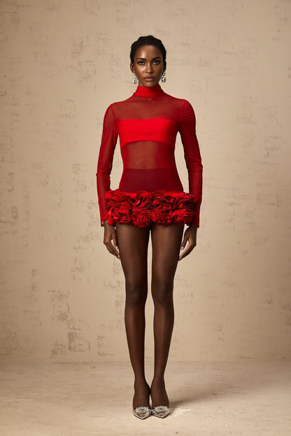 A woman wearing a red mini dress with 3d floral petal details made of semi sheer tulle fabric