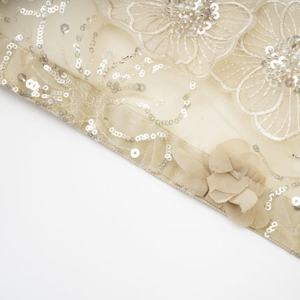 A woman wearing a sheer floral jacket with beaded embellishments and delicate organza fabric in a light luxurious style