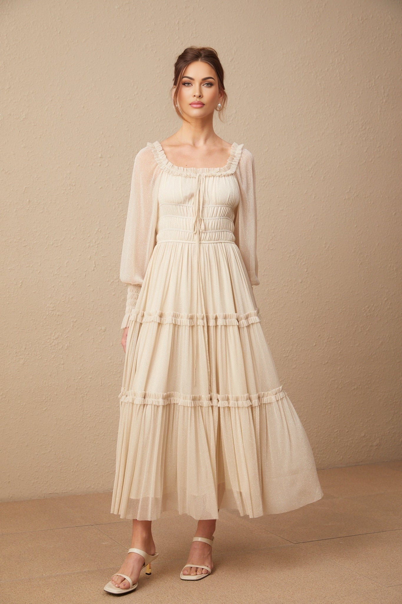 A woman wearing a shimmering metallic midi dress with pleated details and shirred waistline standing in an elegant pose