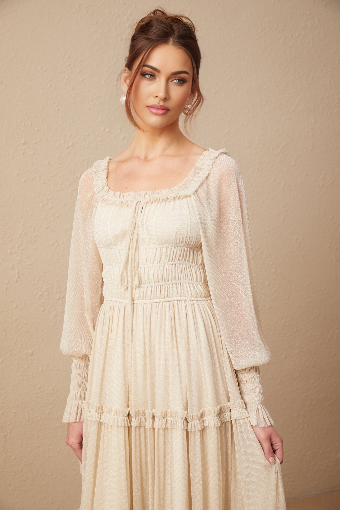 A woman wearing a shimmering metallic midi dress with pleated fabric and shirred detailing