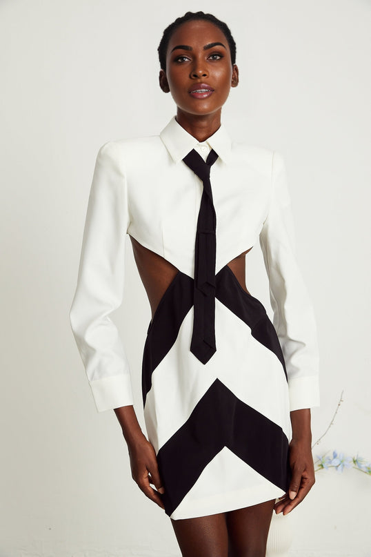 A woman wearing a short black dress with a high neckline tied in a bow and a cutout detail at the chest