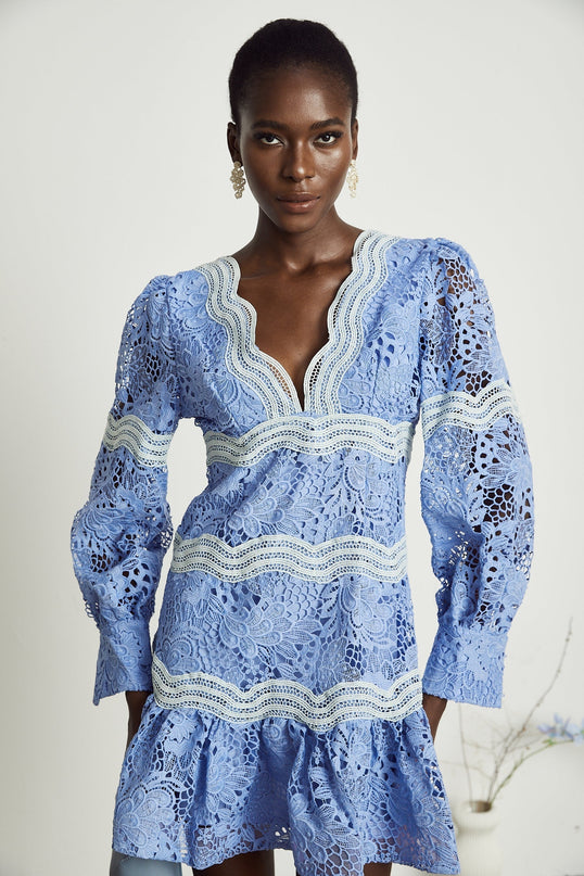 A woman wearing a short floral embroidered mini dress with a V neckline the dress has a vibrant pattern and fitted silhouette