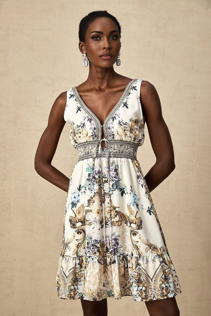 A woman wearing a short floral print dress with a vneckline and short sleeves standing against a light background