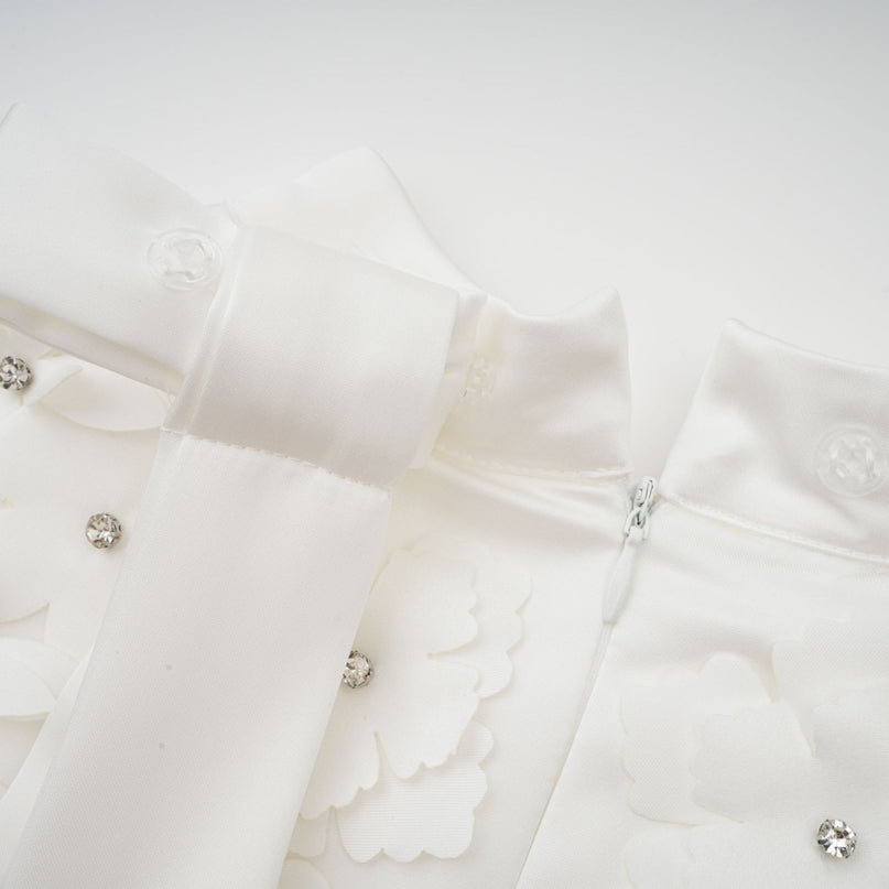 A woman wearing a short floral print dress with vibrant colors and a flowy silhouette standing against a plain background