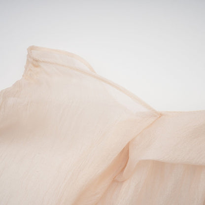 A woman wearing a short offshoulder dress with ruched detailing and layered fabric The dress has selftie straps and falls above the knee The model is posing to showcase the dress design