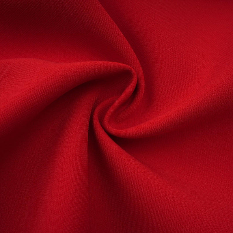 A woman wearing a short red mini dress with cap sleeves standing in a neutral pose
