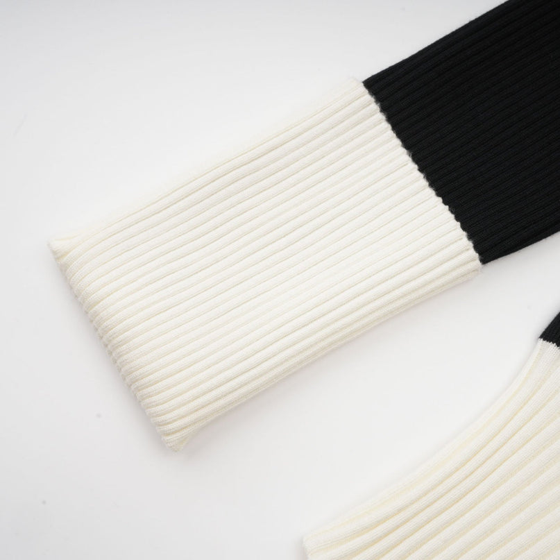 A woman wearing a short ribbed knit dress made of wool The dress features color blocking with different sections in contrasting colors It has a fitted silhouette and ends above the knee