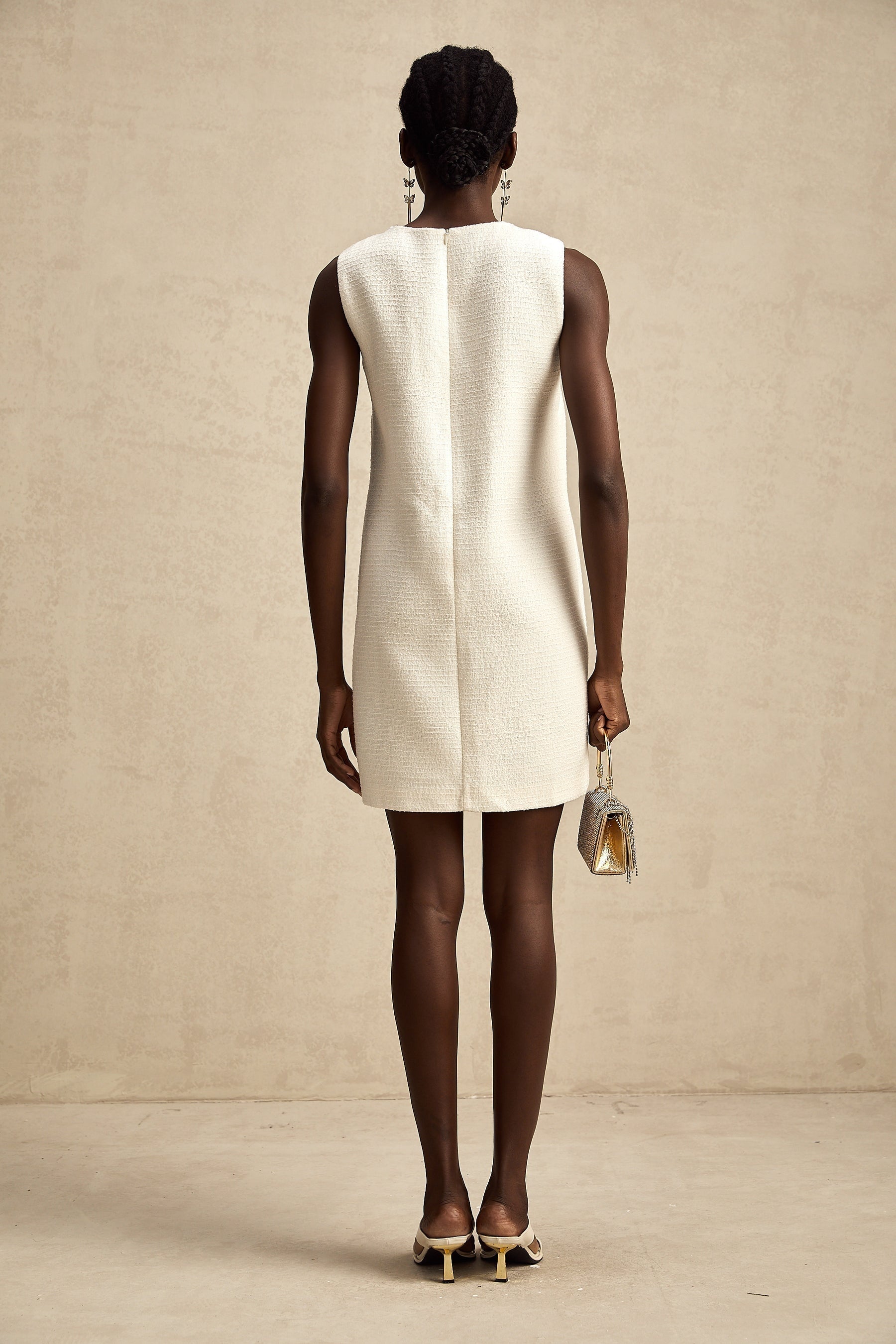 A woman wearing a short tweed dress with embroidery details and cutout sections