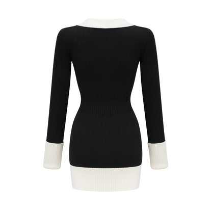 A woman wearing a short wool dress with color blocks and ribbed texture featuring long sleeves and a high neckline