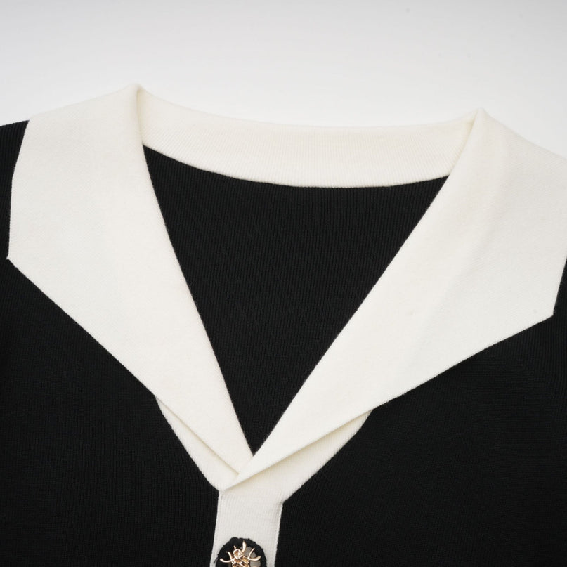 A woman wearing a short wool dress with colorblocked sections and ribbed knit texture featuring long sleeves and a fitted silhouette