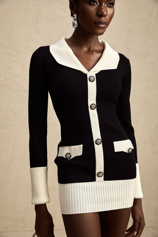 A woman wearing a short wool dress with colorblocked sections and ribbed knit texture in contrasting colors