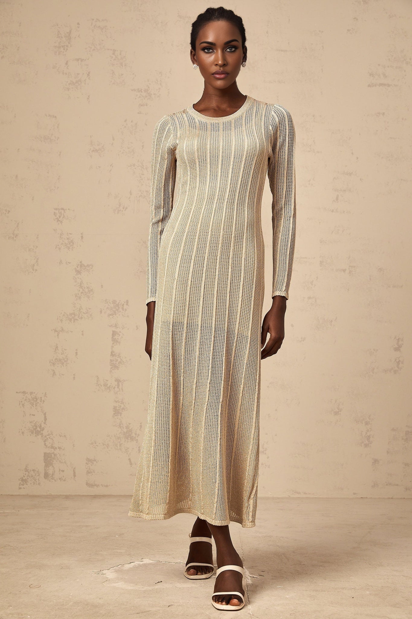 A woman wearing a sleek khaki colored fitted knit midi dress standing in a neutral setting