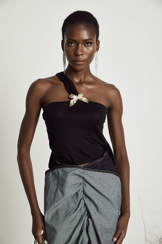 A woman wearing a sleek one shoulder top in a solid color with a fitted silhouette and asymmetrical neckline