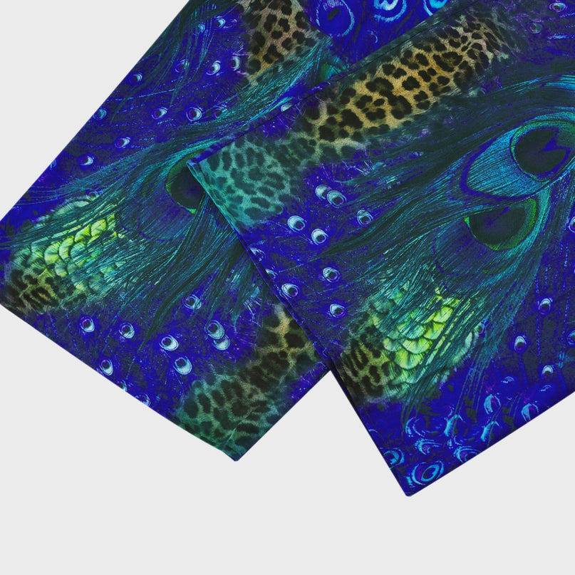 A woman wearing a sleek silk jumpsuit with a halter neckline in a dark color standing in a relaxed pose against a plain background