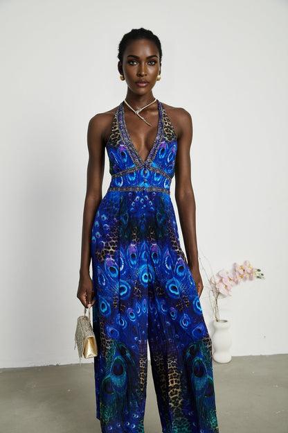 A woman wearing a sleek silk jumpsuit with a halter neckline in a soft flowing fabric the garment drapes elegantly and features a fitted waist with wide leg pants
