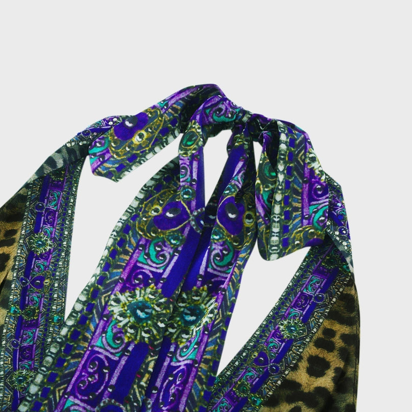 A woman wearing a sleek silk jumpsuit with a halter neckline in a soft flowing fabric The jumpsuit has a fitted bodice and wide leg pants creating an elegant silhouette Perfect for formal occasions or evening wear