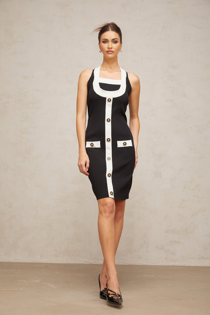 A woman wearing a sleeveless knit mini dress with a halter neckline The dress features color blocking with contrasting sections The model stands in a relaxed pose showing the fitted silhouette of the dress