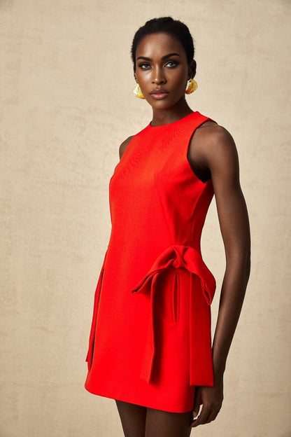 A woman wearing a sleeveless red mini dress with a bow detail