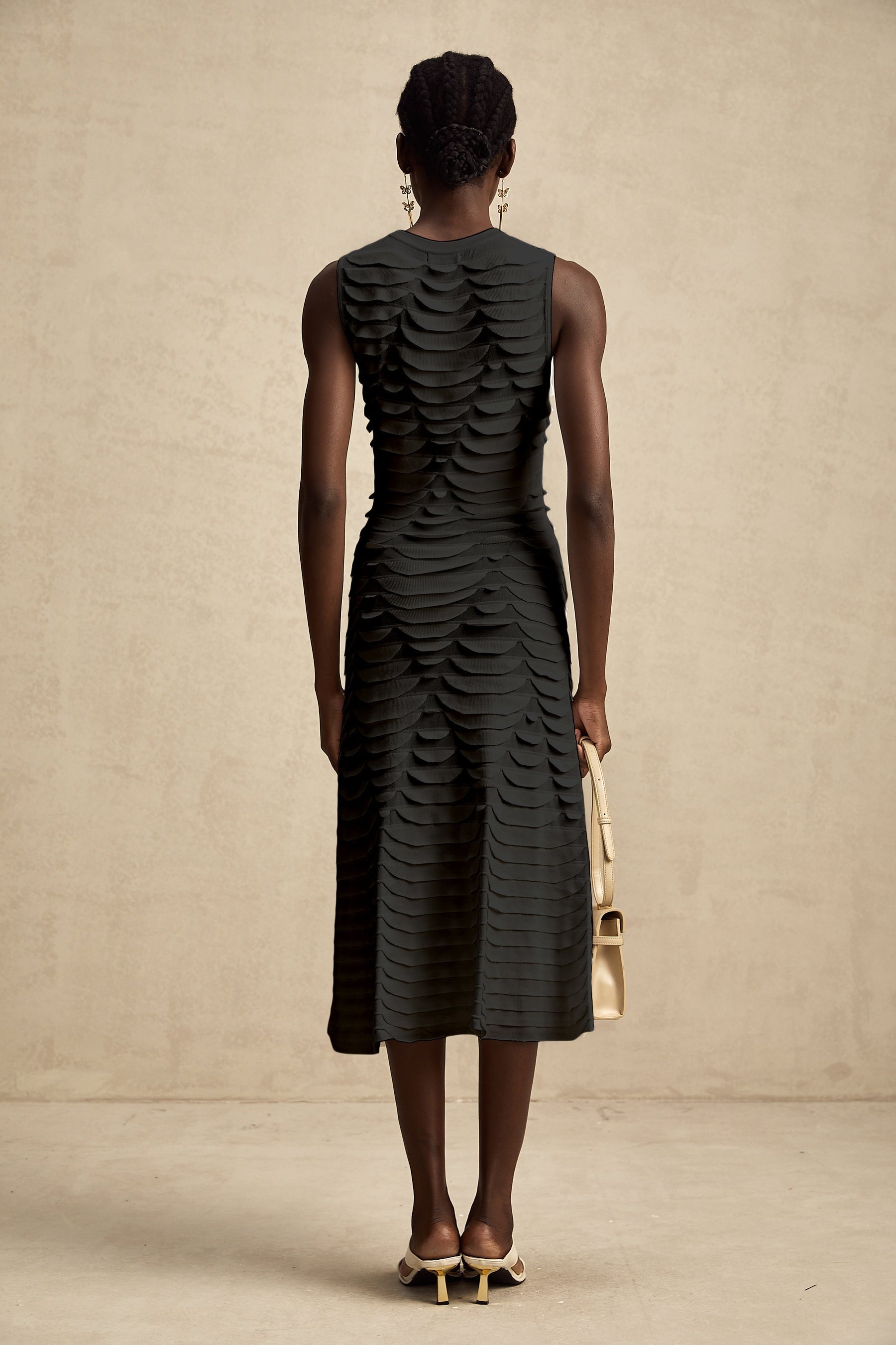 A woman wearing a snakepattern midi dress with a godet skirt the dress has long sleeves and a high neckline the snakeskin pattern is visible across the entire garment