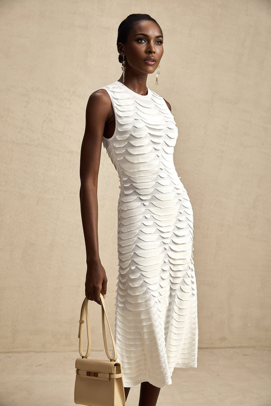 A woman wearing a snakepattern midi dress with godet inserts flaring out from the knees creating a flowing silhouette the dress has long sleeves and a high neckline