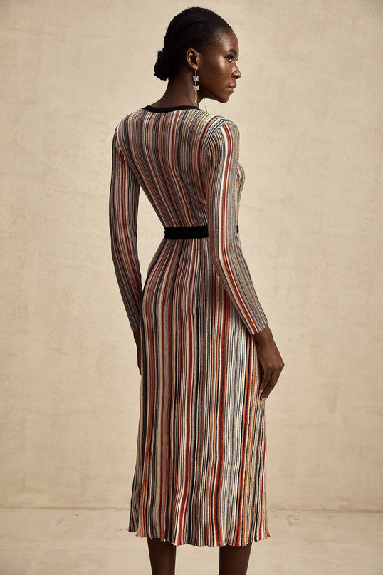 A woman wearing a striped metallic midi dress with a wrap design named Adele standing in a neutral background