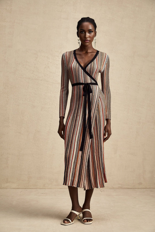 A woman wearing a striped metallic midi dress with a wrap design The dress has a shimmering effect and features diagonal stripes The wrap style accentuates the waistline and creates an elegant silhouette