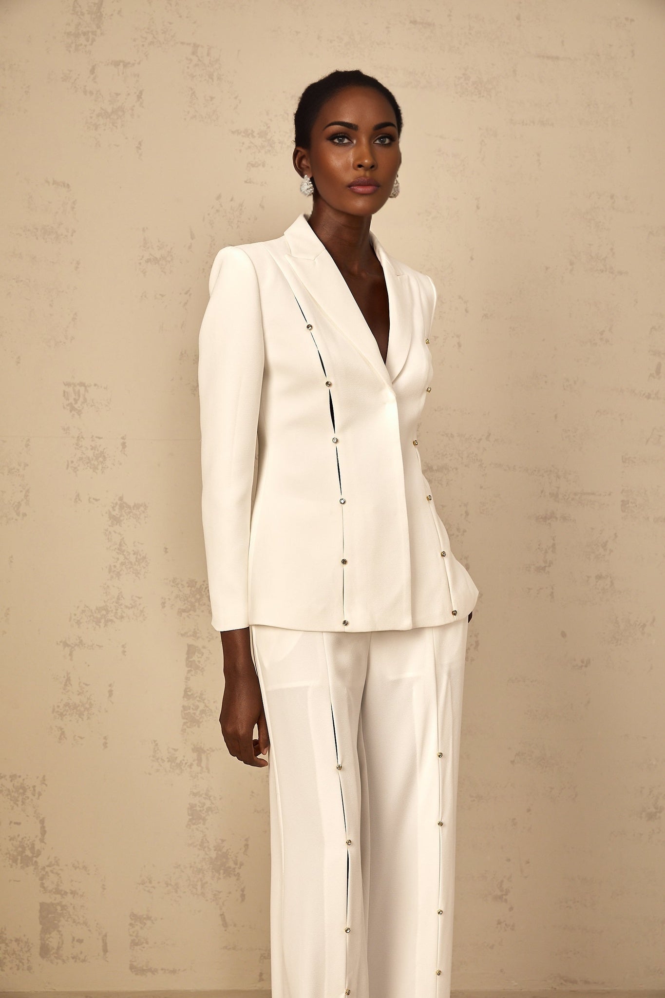 A woman wearing a stylish black blazer and trouser pant set with embellished details The blazer features decorative embroidery or beading while the pants have a sleek tailored fit The outfit is shown on a model or mannequin against a plain background