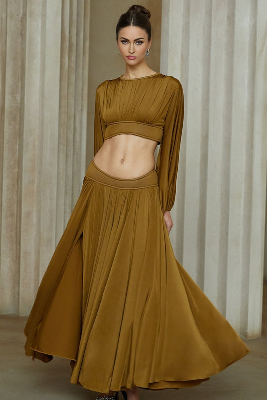 A woman wearing a vibrant green two piece outfit consisting of a fully pleated blouse and matching pleated skirt The ensemble has a flowing elegant appearance with a feminine silhouette