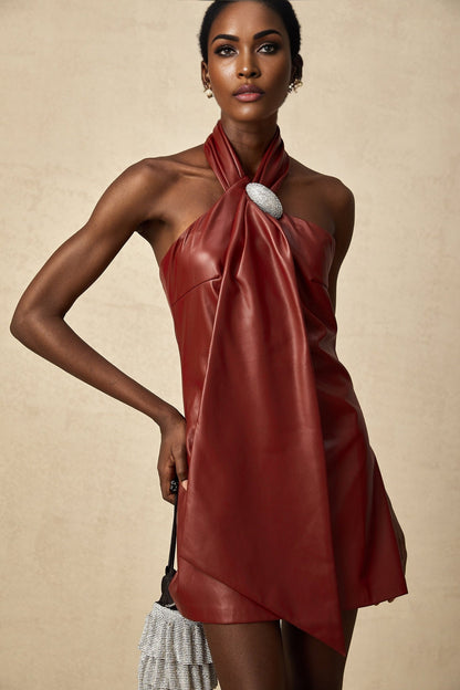 A woman wearing a vibrant red halterneck mini dress made of sheepskin The dress features a form fitting silhouette with a short hemline and a sleek halter neckline