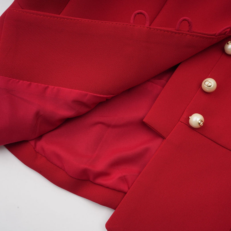 A woman wearing a vibrant red matching set consisting of a pleated blouse and skirt The blouse features a collared neckline and the skirt has a flowy pleated design The outfit is styled as a coordinated ensemble