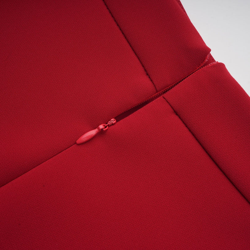 A woman wearing a vibrant red matching set consisting of a pleated blouse and skirt The blouse has a loose fit with pleated details while the skirt falls to about knee length with pleats throughout Both pieces are in a bright red color creating a coordinated outfit